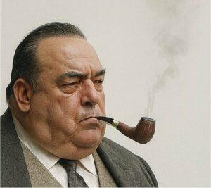 Laurent Chani, a writer with a focused expression, smokes his pipe as the smoke rises in the air