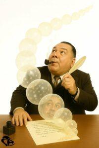 Laurent Chani, assis à son bureau plume en main, observe pensivement une suite de bulles translucides s’élevant dans l’air comme une métaphore de l’imagination | Laurent Chani, seated at his desk with a quill in hand, gazes thoughtfully at a series of translucent bubbles rising into the air as a metaphor for imagination